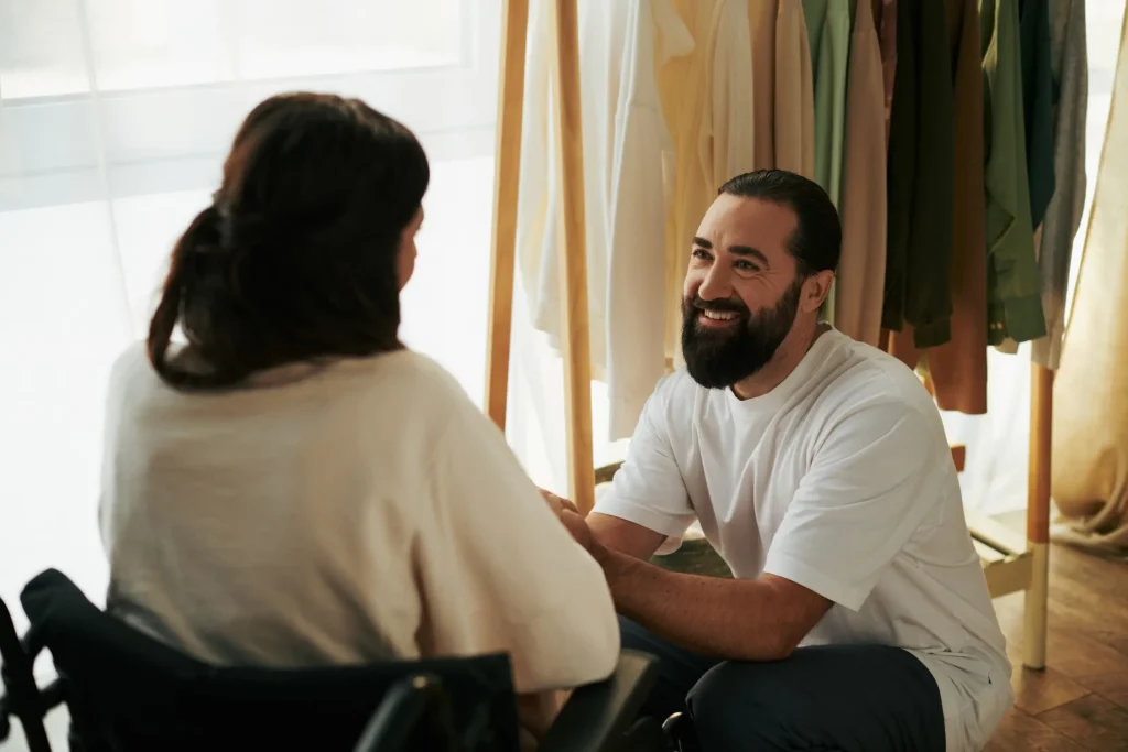 Disabled woman in wheelchair smiling at support worker
