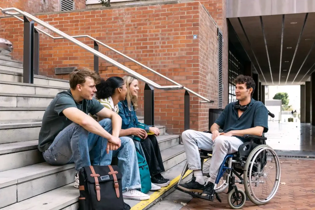 Disabled student in wheelchair chatting with three of his friends